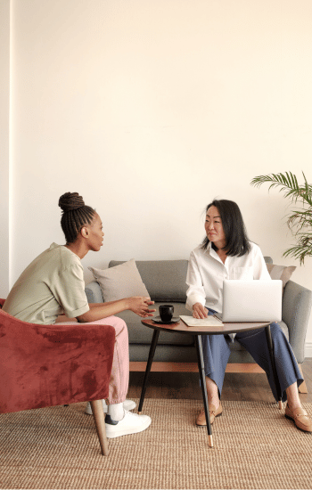 two women discussing EMDR therapy in NYC over a cup of coffee with an apple laptop