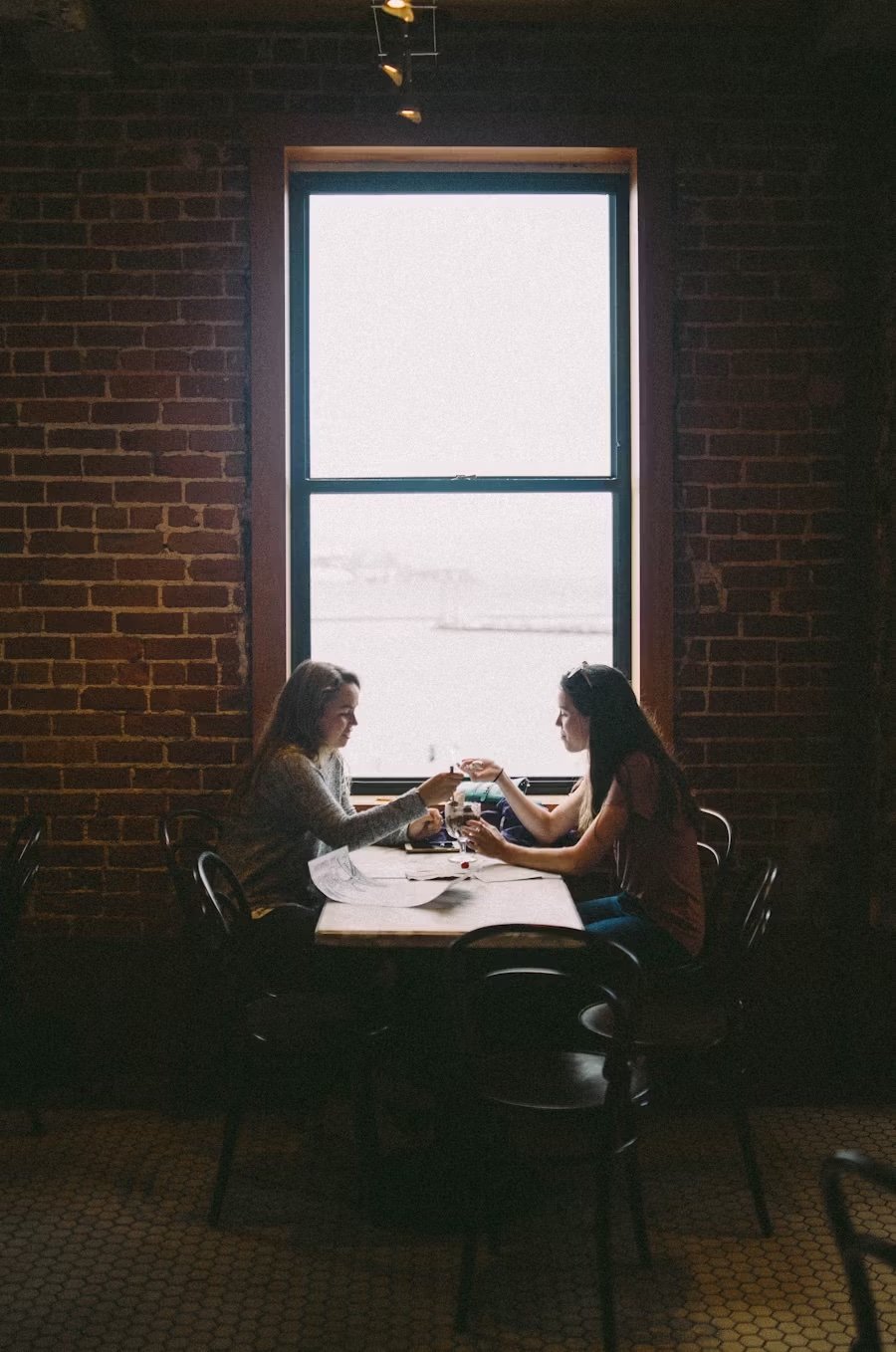 how to navigate your quarter life crisis, illustrated by two women sitting at a table talking with glasses of water