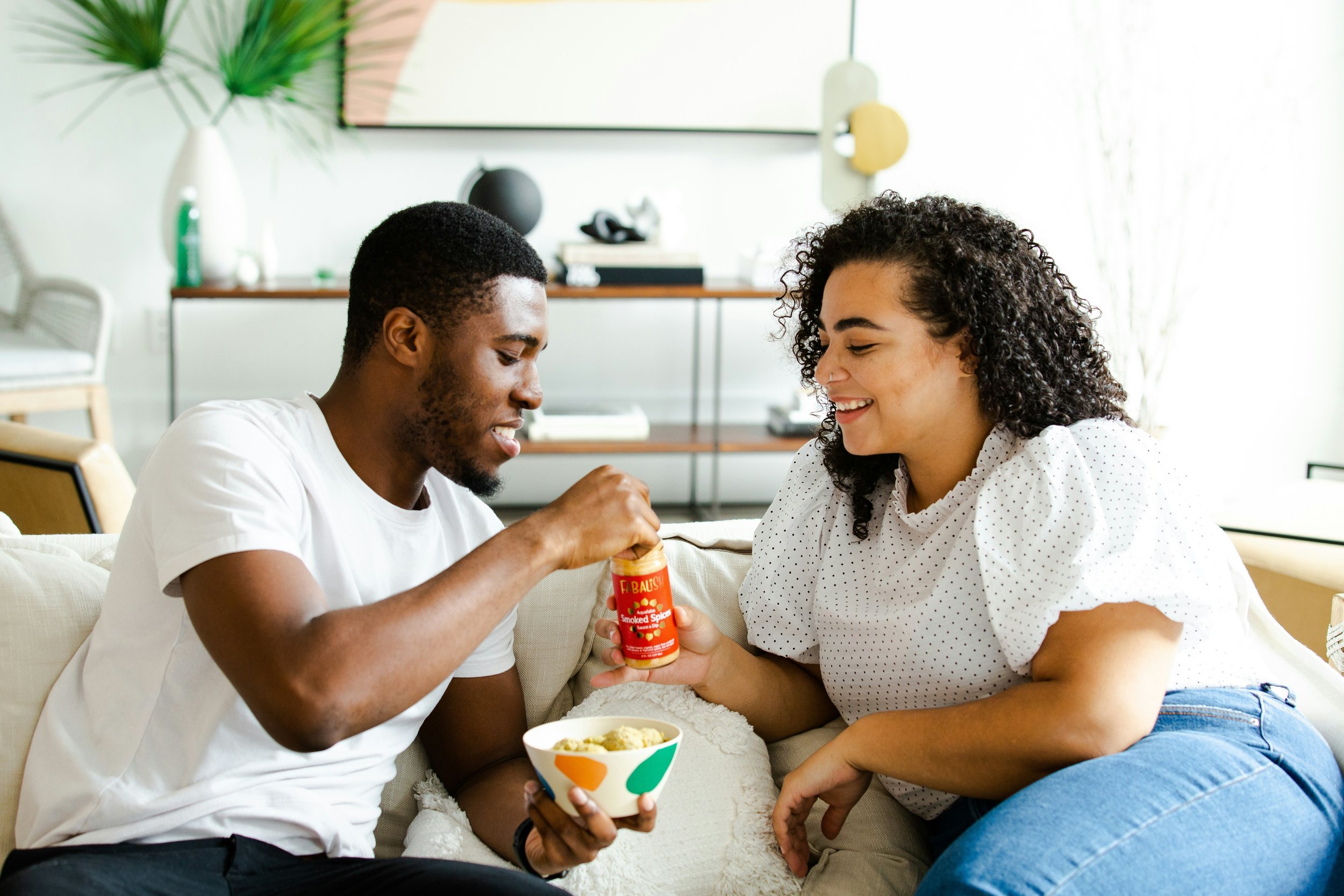 a man and a woman on a couch eating a snack together illustrating how to navigate dating in NYC