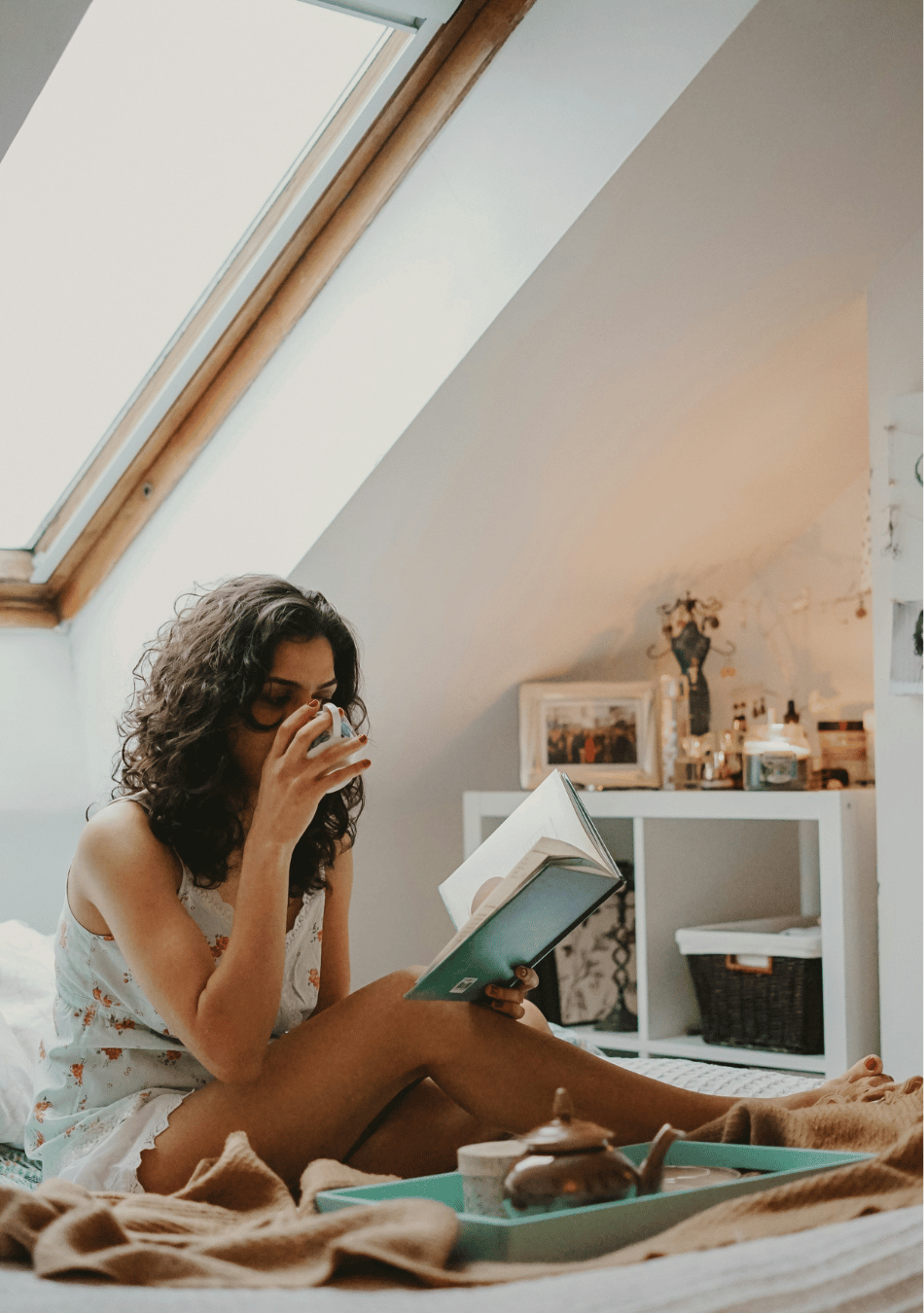a woman reading a book about anxious attachment in a little nook with a cup of tea