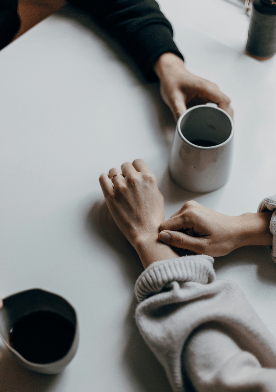 hands of two individuals having coffee discussing how to get out of a relationship rut