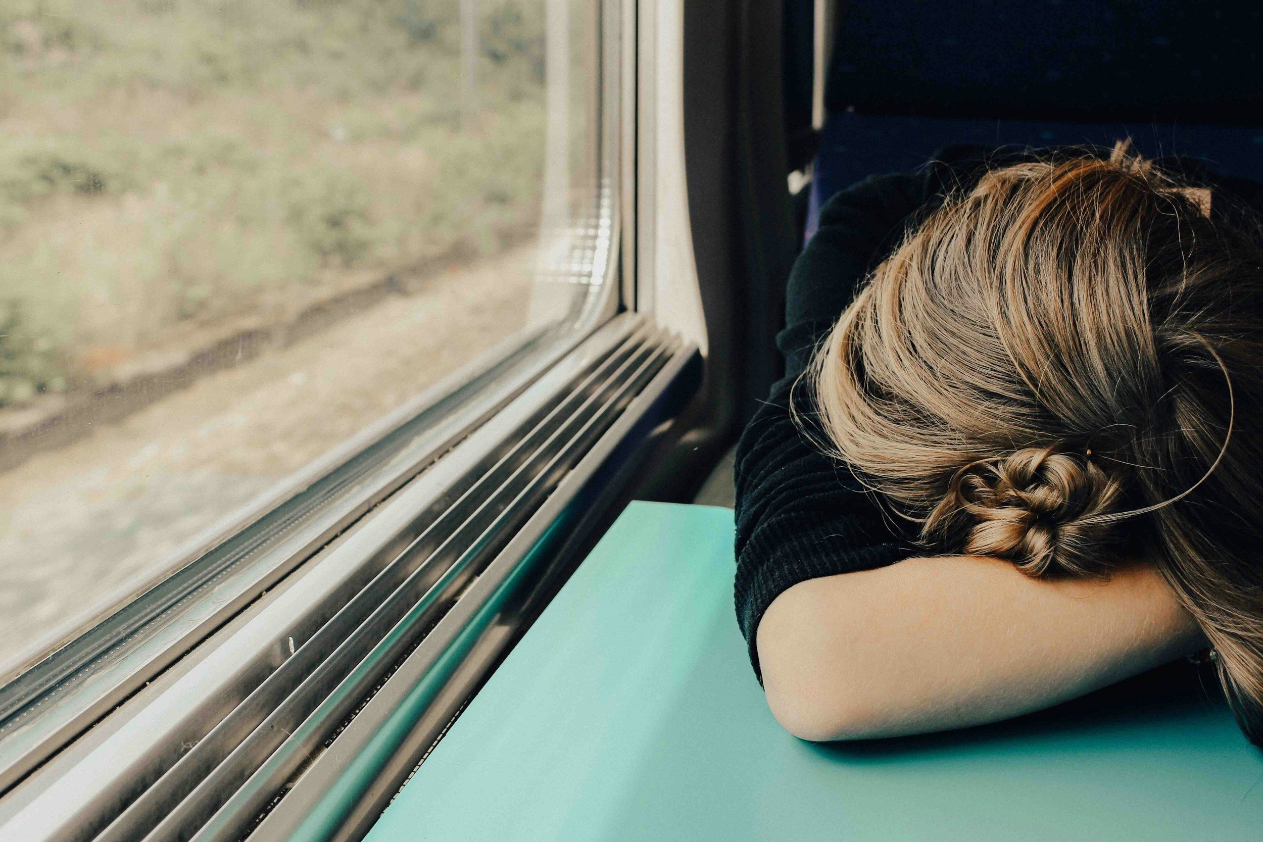 how to recover from burnout illustrated by a woman with her head down on a table in a train