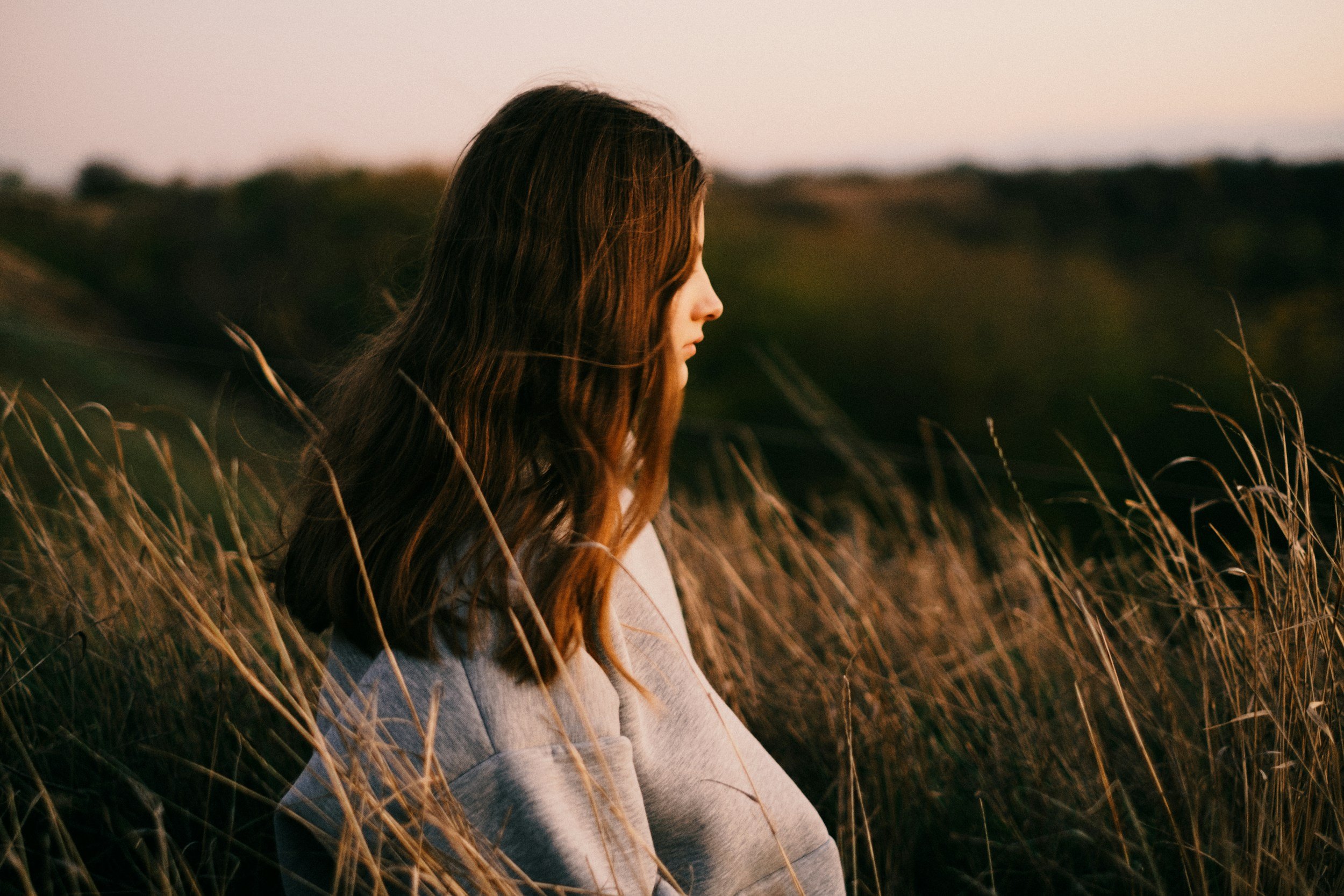anxiety attacks vs panic attacks illustrated by a woman sitting in tall grass looking at the horizon